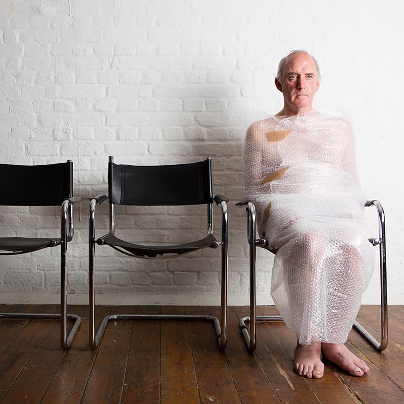 Photo shoot in the studio man seated wrapped in cling film