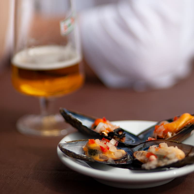  Stuffed Mussels on a dish with a beer out of focus in the background.