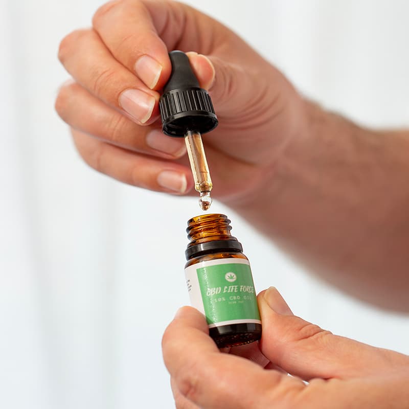 Close up of mans hands opening a small bottle of CBD oil showing how the pipette works.