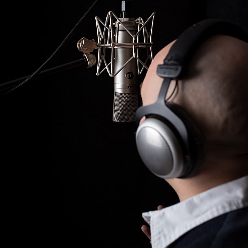 Close up picture of a man singing into Mic.