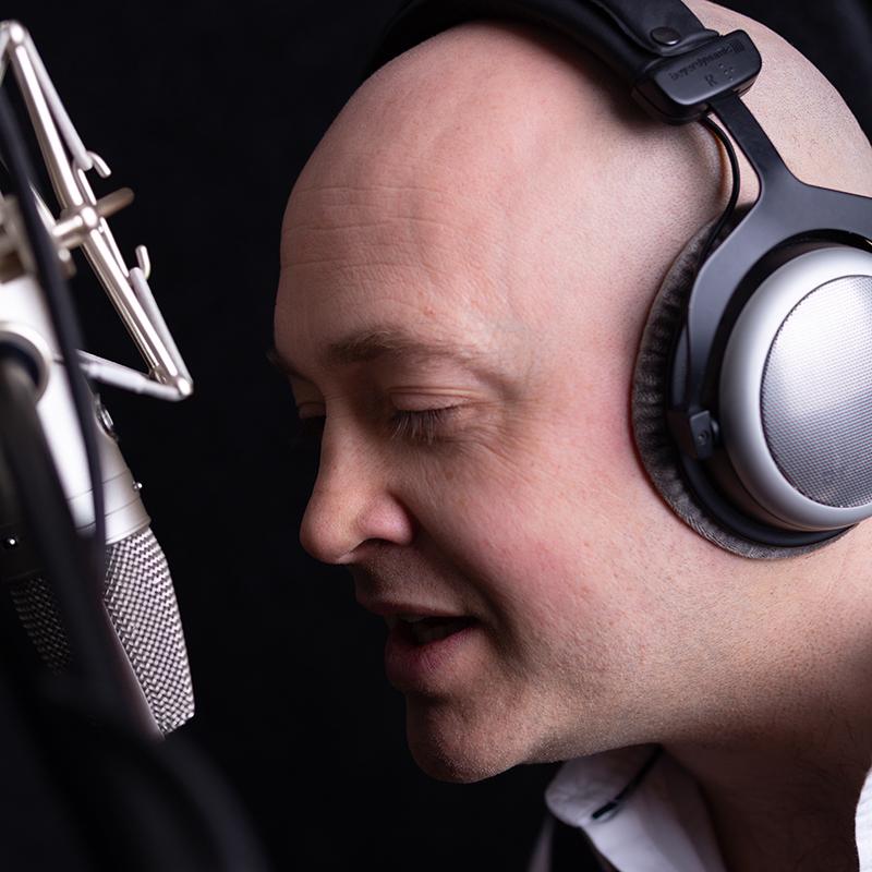 Portrait of man speaking in to a mic wearing headphones