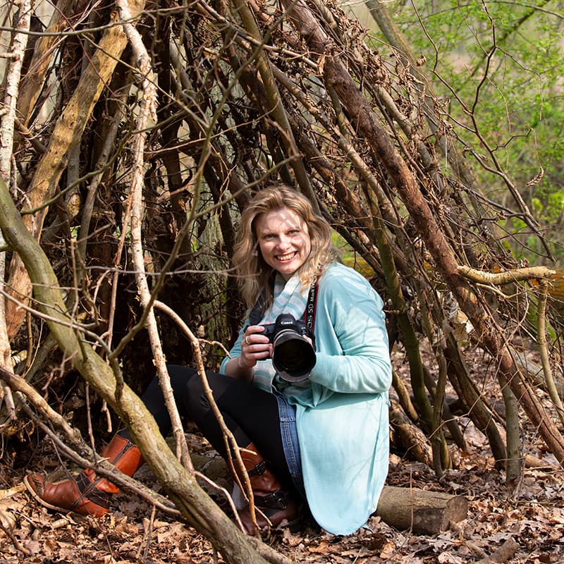 Photographer posing by a pile of wood