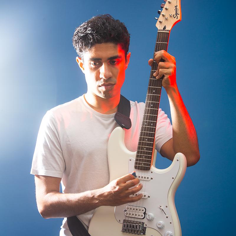 Man playing the guitar against blue background