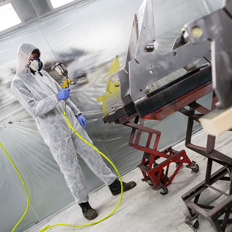 Photo of man spray painting some metal