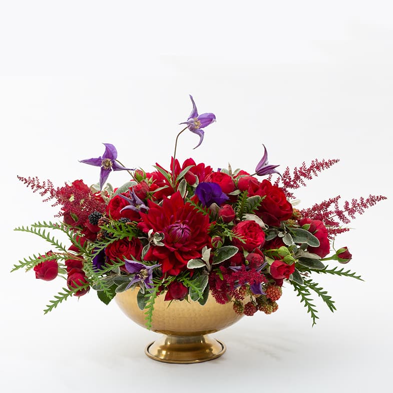 Dark red and purple flowers in a gold vase.